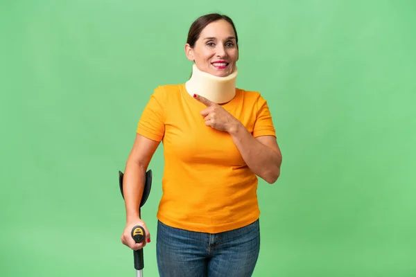 stock image Middle-aged caucasian woman wearing neck brace over isolated background pointing to the side to present a product