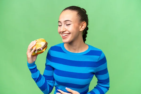 Young Arab Woman Holding Burger Isolated Background Smiling Lot — Stock Photo, Image