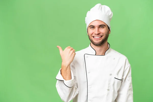 Mladý Pohledný Kuchař Muž Přes Izolované Pozadí Ukazuje Stranu Prezentovat — Stock fotografie