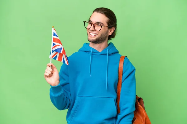 年轻英俊的男子举着英国国旗 背景偏僻 向侧面看去 面带微笑 — 图库照片