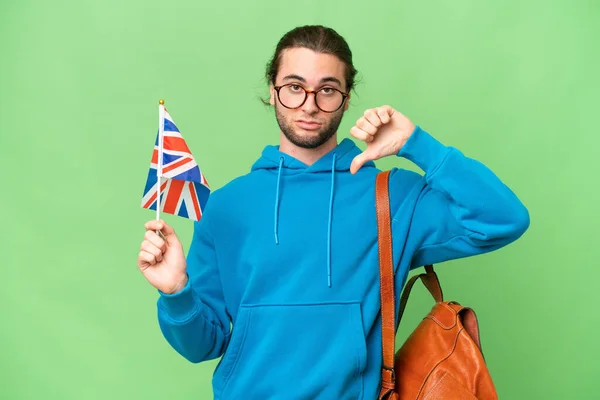 年轻英俊的男子举着英国国旗 身披孤立的背景 带着负面的表情垂头丧气 — 图库照片
