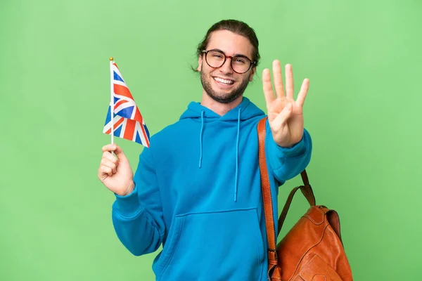 年轻英俊的男子举着英国国旗 高高兴兴地坐在孤立的背景上 手指头数着四个 — 图库照片
