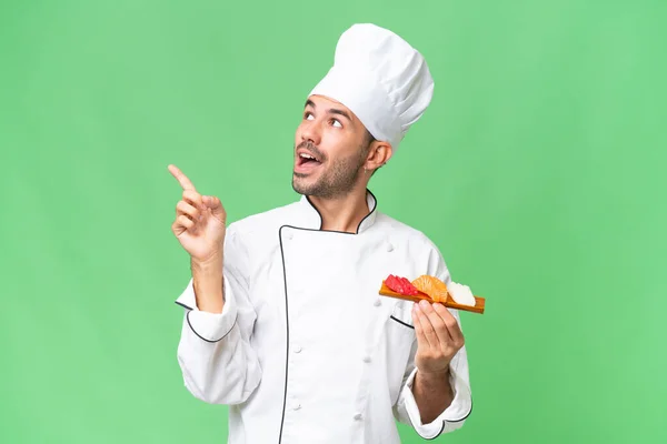 Young Caucasian Chef Holding Sushi Isolated Background Intending Realizes Solution — Stock Photo, Image