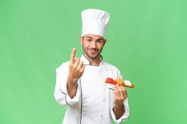 Joven Chef Caucásico Sosteniendo Sushi Sobre Fondo Aislado Haciendo Gesto — Foto de Stock