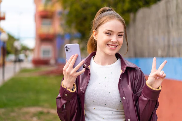 Jong Mooi Meisje Met Behulp Van Mobiele Telefoon Buiten Glimlachen — Stockfoto