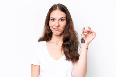 Beyaz arka planda hüzünlü bir ifadeyle ev anahtarlarını tutan beyaz bir kadın.