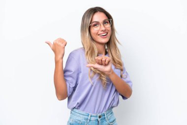 Genç Uruguaylı kadın beyaz arka planda izole edilmiş bir ürün sunmak için kenarı işaret ediyor.