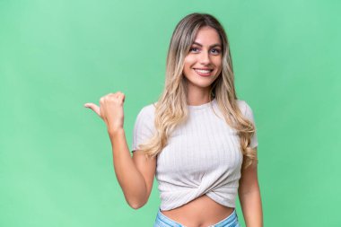 Genç Uruguaylı kadın, izole edilmiş arka planda bir ürünü sunmak için kenarı işaret ediyor.