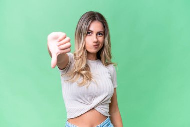 Genç Uruguaylı kadın izole edilmiş arka planda, olumsuz bir ifadeyle baş parmağını aşağı gösteriyor.