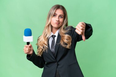 Genç, güzel Uruguaylı televizyon sunucusu, izole edilmiş arka planda, olumsuz ifadeyle baş parmağını aşağı gösteriyor.