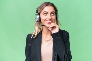 Tele pazarlamacı güzel Uruguaylı kadın izole edilmiş bir arka planda kulaklıkla çalışırken bir fikir arıyor.