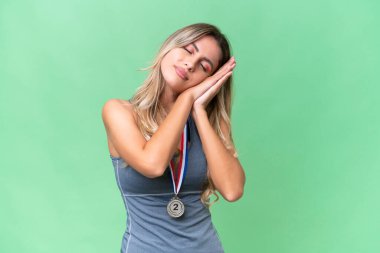 İzole edilmiş arka planda madalyaları olan genç ve güzel bir Uruguaylı kadın, hareketli bir uyku hareketi yapıyor.