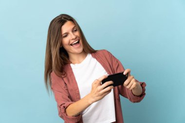 Genç Slovak kadın mavi arka planda izole edilmiş cep telefonuyla oynuyor