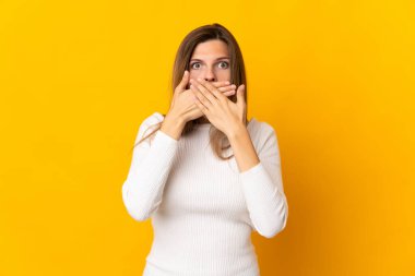 Sarı arka planda izole edilmiş genç Slovak kadın elleriyle ağzını kapatıyor.