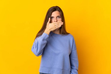 Sarı arka planda izole edilmiş genç Slovak kadın ağızlarını eliyle kapatıyor.