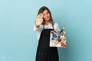 Genç sanatçı Slovak kadın, mavi arka planda izole edilmiş bir şekilde duruyor.