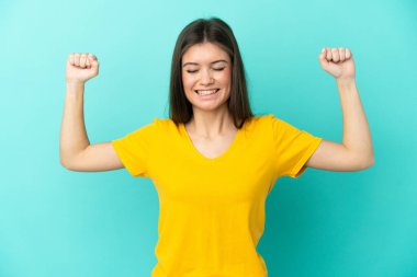 Mavi arka planda izole edilmiş beyaz bir kadın güçlü bir jest yapıyor.