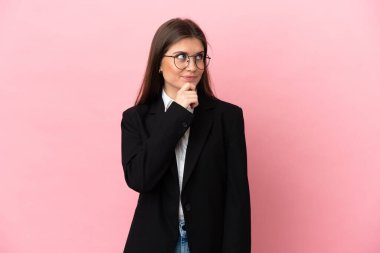 Genç beyaz kadın pembe arka planda izole edilmiş ve araştırılıyor.