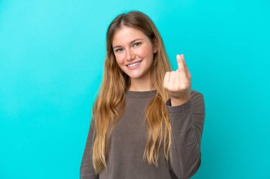 Mavi arka planda izole edilmiş genç sarışın kadın para hareketi yapıyor.