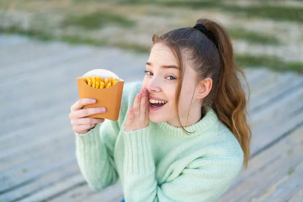 Joven Chica Bonita Sosteniendo Papas Fritas Aire Libre Susurrando Algo —  Fotos de Stock