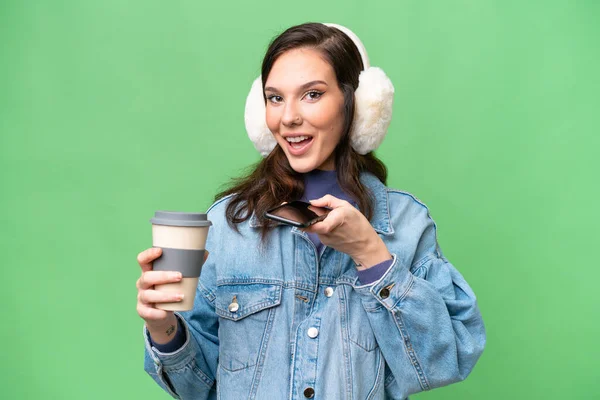 Young Caucasian Woman Wearing Winter Muffs Isolated Background Holding Coffee — Stock Photo, Image