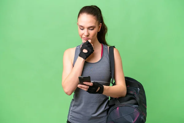 孤立した背景思考とメッセージを送信する上でスポーツバッグを持つ若いスポーツ女性 — ストック写真