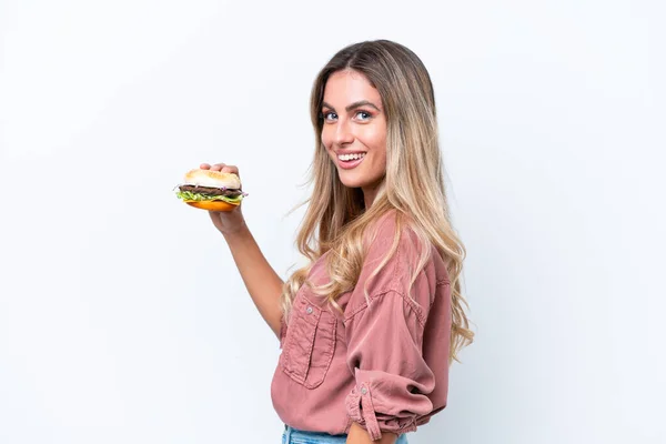 Młoda Ładna Urugwajska Kobieta Trzyma Hamburgera Odizolowany Białym Tle Uśmiechając — Zdjęcie stockowe