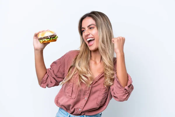 Fiatal Csinos Uruguayi Kezében Egy Hamburger Elszigetelt Fehér Háttérrel Ünneplő — Stock Fotó