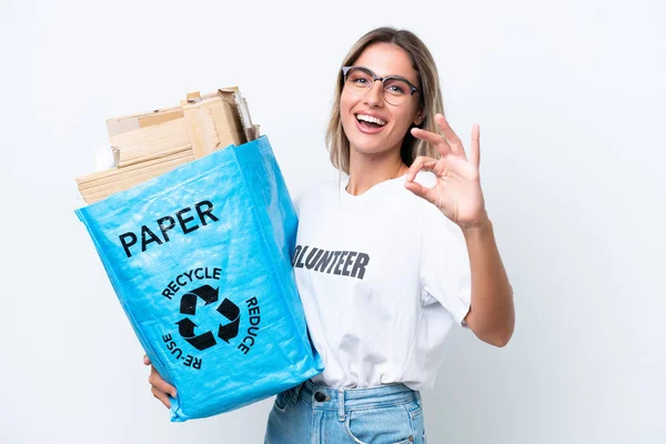 若いですかなりウルグアイの女性を保持リサイクルバッグフル紙でリサイクルするために白いクロマの背景に隔離された指でOkサインを示す — ストック写真
