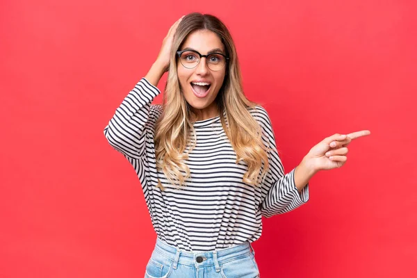 stock image Young Uruguayan woman isolated on red background surprised and pointing finger to the side