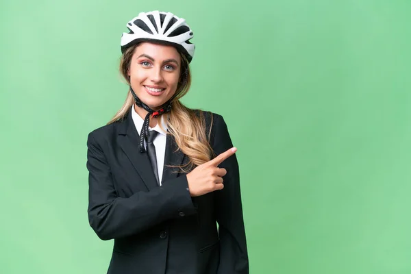 ビジネスウルグアイの女性は 製品を提示する側を指して隔離された背景にヘルメットバイカーを身に着けています — ストック写真