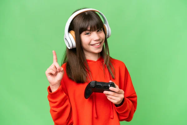 在孤立的背景下与电子游戏控制器玩耍的一个高加索小女孩 伸出一个手指表示最好的迹象 — 图库照片
