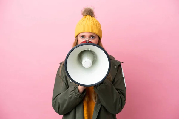 stock image Young blonde woman wearing winter jacket isolated on pink background shouting through a megaphone