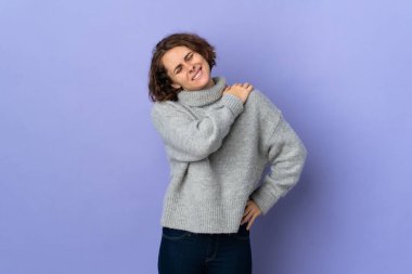 Young English woman isolated on purple background suffering from pain in shoulder for having made an effort