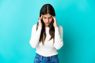 Kafkasyalı genç bir kadın mavi arka planda izole edilmiş, baş ağrısı var.