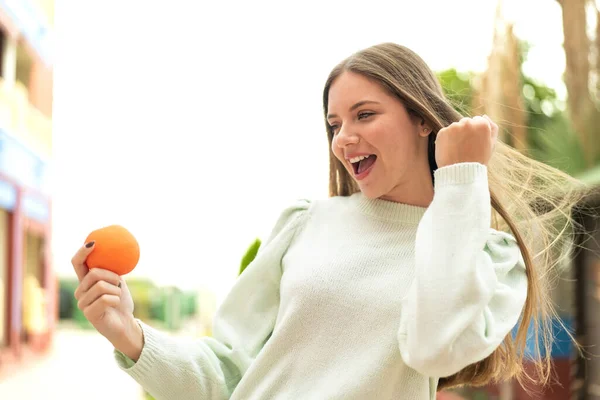 Dışarıda Elinde Portakal Tutan Güzel Sarışın Bir Kadın Zaferi Kutluyor — Stok fotoğraf
