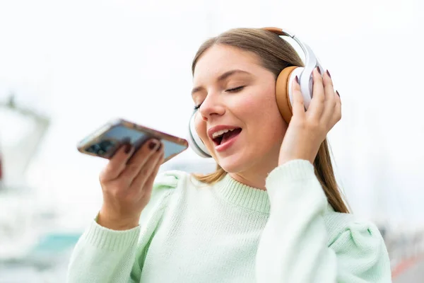 Ung Söt Blond Kvinna Lyssnar Musik Med Mobil Och Sång — Stockfoto
