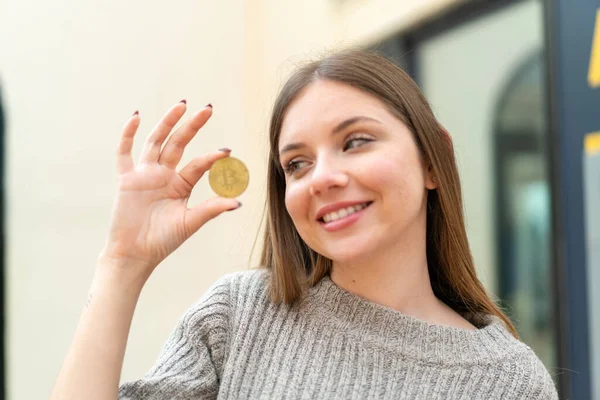 Νέα Όμορφη Ξανθιά Γυναίκα Κρατώντας Ένα Bitcoin Και Αναζητούν — Φωτογραφία Αρχείου