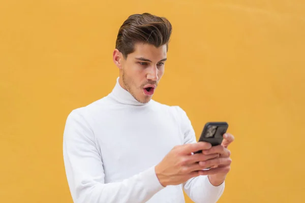 Молодий Білий Чоловік Відкритому Повітрі Дивиться Камеру Використовуючи Мобільний Здивованим — стокове фото