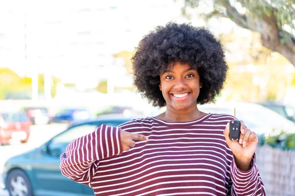 African American girl holding car keys at outdoors with surprise facial expression