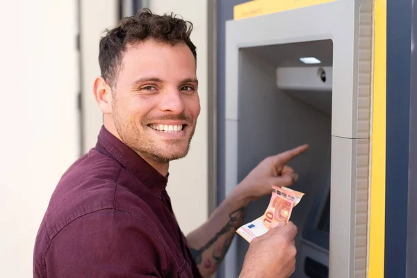 stock image Young caucasian man at outdoors using an ATM