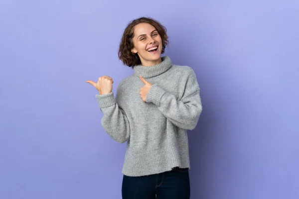 stock image Young English woman isolated on purple background pointing to the side to present a product