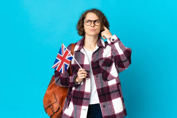 Молодая Английская Женщина Держащая Флаг Великобритании Голубом Фоне Сомневается Думает — стоковое фото