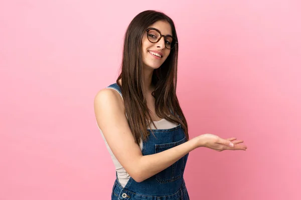 stock image Young caucasian woman isolated on pink background presenting an idea while looking smiling towards