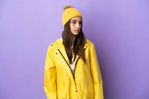 年轻的高加索女人穿着防雨外套 与紫色背景隔离 向侧面看去 — 图库照片
