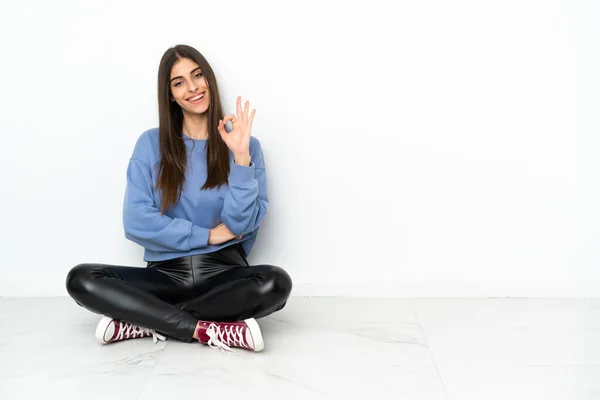 Молодая Женщина Сидящая Полу Изолированы Белом Фоне Показывая Знак Пальцами — стоковое фото