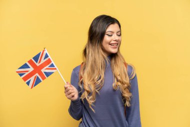 Sarı arka planda izole edilmiş bir Birleşik Krallık bayrağı tutan genç Rus kız.