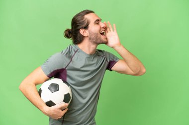 Genç yakışıklı futbolcu, izole edilmiş arka planda ağzı açık bağırıyor.