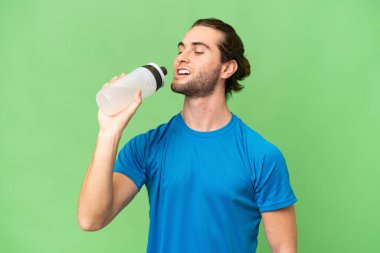 Yeşil krom arka planda izole edilmiş genç yakışıklı bir adam ve spor su şişesi.