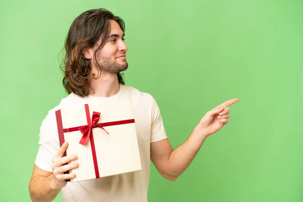 Young Handsome Man Holding Gift Isolated Background Pointing Side Present — Stock Photo, Image